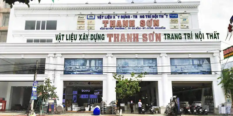 Cửa hàng Việt Nam với biển hiệu cho doanh nghiệp vật liệu xây dựng và trang trí nội thất 'Thanh Son'.